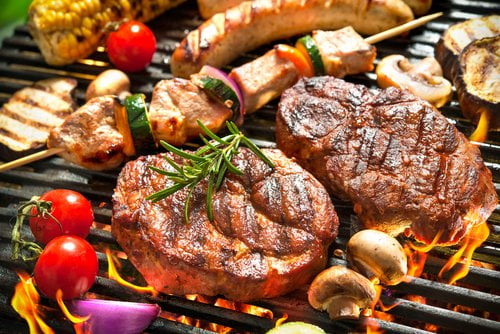 Assorted grilled meats and vegetables on a barbecue grill, showcasing high-protein meal options.